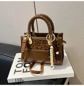 Détail du sac à main en cuir léopard avec poignées tressées et breloque en perles