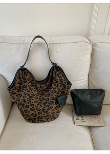 Détail du sac cabas léopard avec pochette noire sur un canapé beige minimaliste