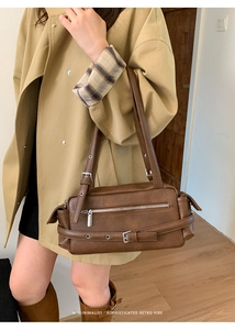 Minimalist retro dark brown pillow bag with silver buckle details shown on shoulder