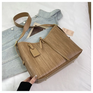 Dettaglio borsa shopper marrone con trama a righe e borchie dorate in un contesto casual