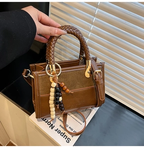 Détail du sac en cuir marron avec poignée tressée et accessoires dorés chic
