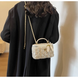 Detail of tweed crossbody bag with chain strap and gold camellia flower logo accent