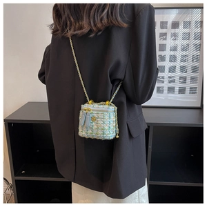 Mini sac bandoulière en tweed avec chaîne dorée et détail floral sur un mannequin