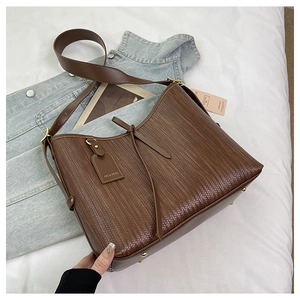 Dettaglio della trama in pelle intrecciata e dei perni metallici sulla borsa tote marrone