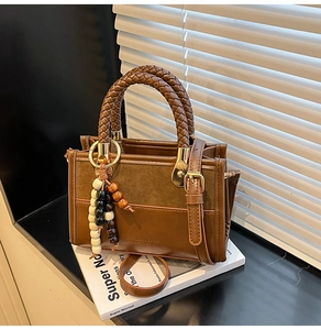 Détail du sac en cuir marron avec poignée tressée et charmant pendentif en perles de bois