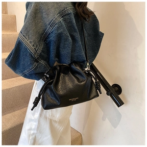 Chic black drawstring bucket bag with lychee texture and gold logo on a model