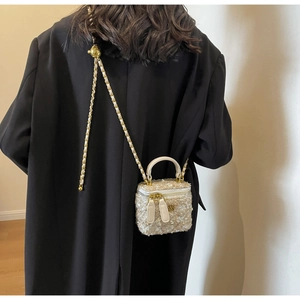 Detail of tweed box bag with camellia metal logo and adjustable gold ball chain
