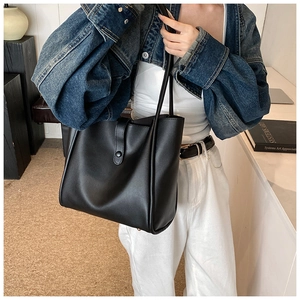 Grand sac fourre-tout noir minimaliste en cuir avec fines lanières porté par un mannequin