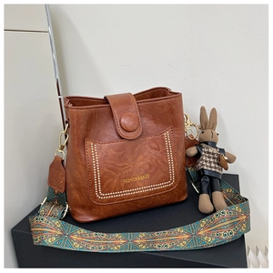 Close-up of vintage brown leather bucket bag with geometric strap and bunny charm