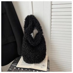 Close-up of black plush shoulder bag with curly faux fur texture on a lifestyle background