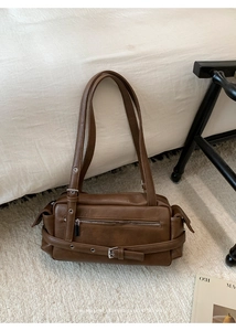 Detail view of retro brown leather shoulder bag with metallic eyelets and zipper details