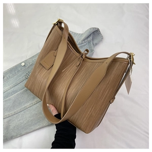 Dettaglio borsa shopper intrecciata marrone con manici in pelle e fibbie dorate
