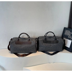 Close-up of canvas duffel bags with leather accents and adjustable shoulder straps