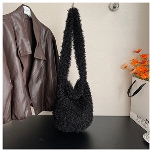 Close-up of black fuzzy faux fur tote bag showing plush curly shearling texture