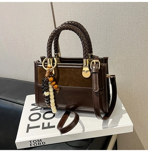 Détail d'un sac à main en cuir marron foncé avec couture contrastée et bijou de sac
