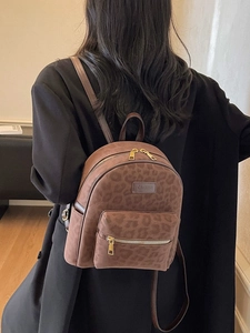 Leopard print backpack with matte finish and gold hardware worn by a model in black blazer