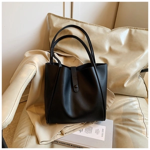 Détail du grand sac cabas noir en similicuir avec boucle sur un fond de ton neutre