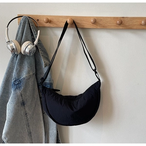 Detail of black nylon crescent bag with adjustable strap on a wooden hanger