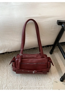 Detailed macro view of dark red vintage leather bag with metal buckles and zippers
