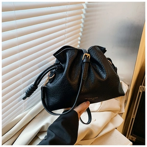 Detail of black lychee grain leather bucket bag with gold metal buckle and drawstring
