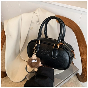 Detail of black vintage Boston bag with letter embossing and plush charm on blazer
