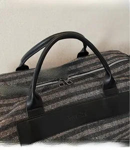 Detail of travel duffel bag with herringbone fabric, metal zippers and sturdy leather handles