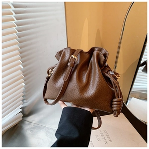 Detail of dark brown lychee textured leather cloud bag with decorative side knots