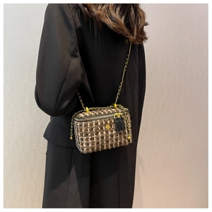 Dettaglio della mini borsa a secchiello in tweed con logo a fiore dorato e catena