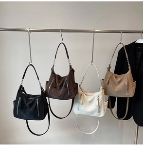 Row of textured hobo bags in four colors on a metal rack with a black office blazer