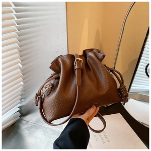 Detail of brown pleated bucket bag showing leather texture and side knot design