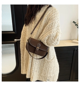Detail of dark brown vintage matte leather crossbody bag worn with a beige sweater