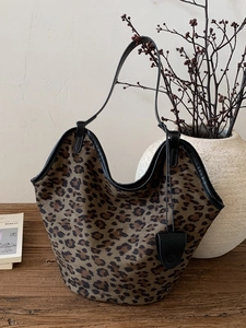 Grand sac cabas en daim léopard avec lanières en cuir noir sur table en bois
