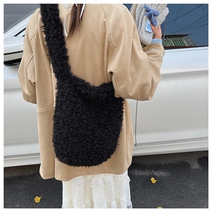 Detailed close-up of a large black plush faux fur shoulder bag with wide strap on a model