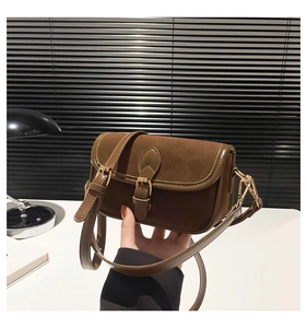 Detail view of retro brown crossbody bag featuring suede patchwork and gold buckle