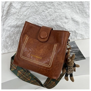 Detailed close-up of retro brown bucket bag with studded logo and geometric strap