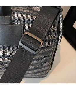 Detail of adjustable shoulder strap with matte buckle and herringbone fabric on sports bag