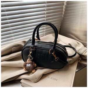 Detail of black bowling bag with ATN logo embossing and a brown plush monster charm