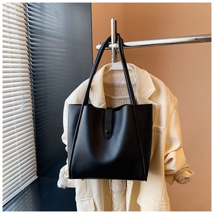 Détail d'un grand sac cabas en cuir noir avec fermoir magnétique sur une veste