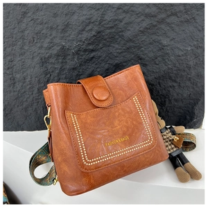 Detail of vintage brown bucket bag with decorative pocket and embroidered strap