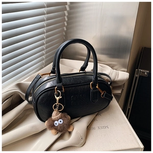 Detail showing vintage black faux leather boston bag texture with plush monster charm