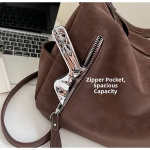 Detail view of the side zipper pocket on a brown faux leather tote bag for storage