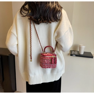 Pink tweed crossbody box bag with leather handle and chain strap worn by a model