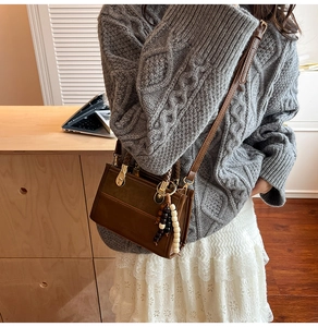 Détail d'un sac bandoulière en cuir marron avec perles sur mannequin dans un décor chaleureux