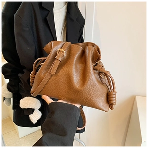 Close-up of brown textured leather bucket bag with drawstring and knot detail