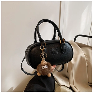 Detail of black textured leather bowling bag with ATN logo and brown plush charm