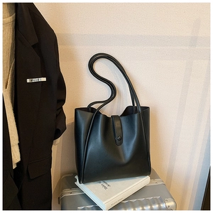 Détail du sac cabas en cuir noir avec fermeture à pression et doubles bretelles minimalistes