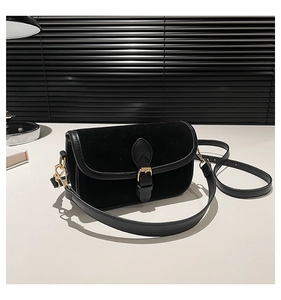Detail of black velvet crossbody bag with gold buckle and smooth leather trimming