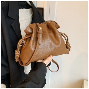 Brown lychee leather bucket bag with adjustable strap and knot detailing close-up