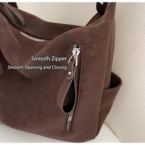 Detail of smooth metal zippers and vintage faux leather texture on dark brown tote bag