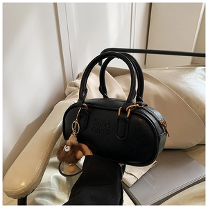 Detail view of black leather bowling bag with embossed ATN logo and plush charm
